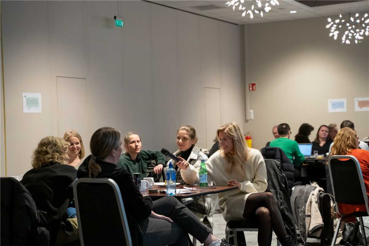 Bilde frå plenumsdiskusjon ein deltakar gir mikrofon til ein annan - Klikk for stort bilete